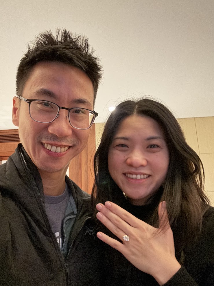 Selfie of Bernard and Rebecca after the engagement &mdash; both smiling, Rebecca's left hand raised to show her ring.